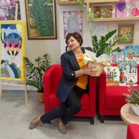 Kobieta siedzi na czerwonym fotelu w dłoniach trzyma kwiaty